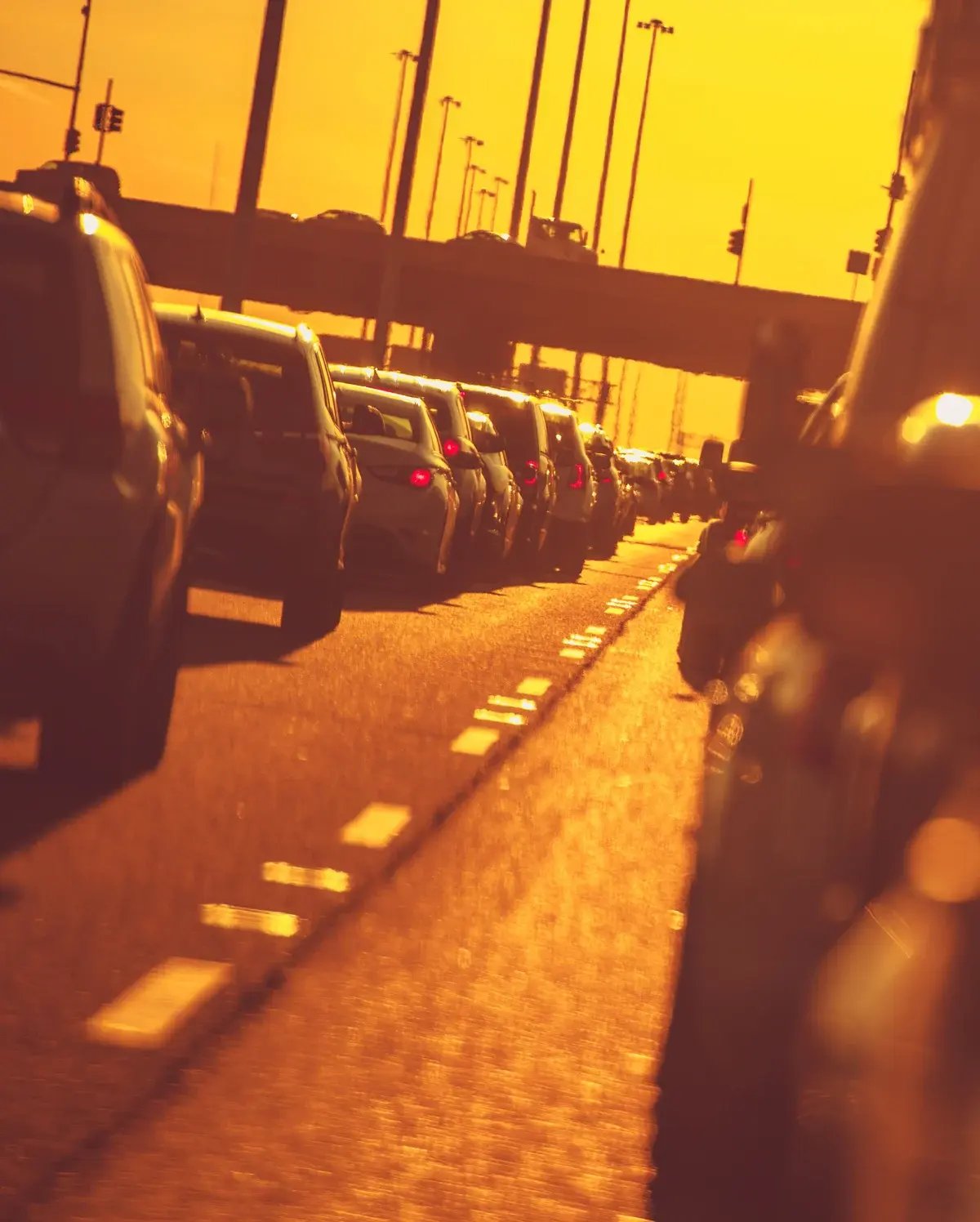 A vertical shot of heavy highway traffic jam at sunset, with car silhouettes against a warm orange glow