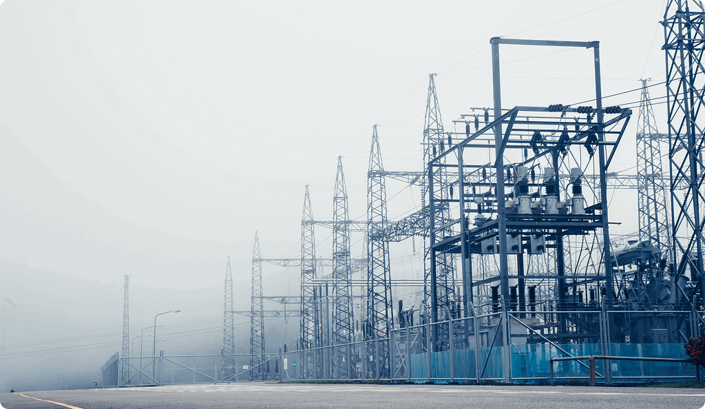 A large electrical power substation with high-voltage transmission towers stretching into the distance