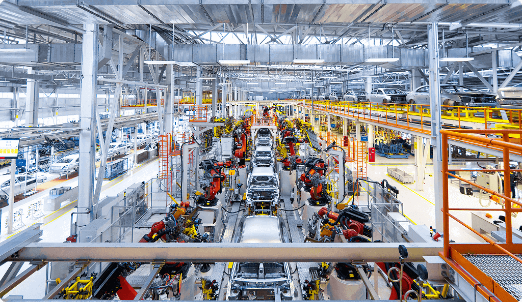 A wide view of a large automotive manufacturing assembly line with numerous industrial robots working on car bodies