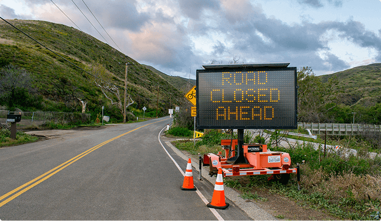 Portable electronic sign displaying 'ROAD CLOSED AHEAD