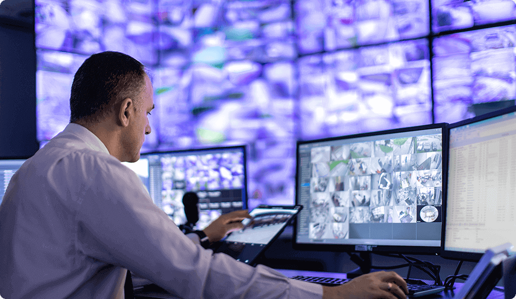 A security operator monitoring numerous surveillance feeds on a large, multi-screen video wall
